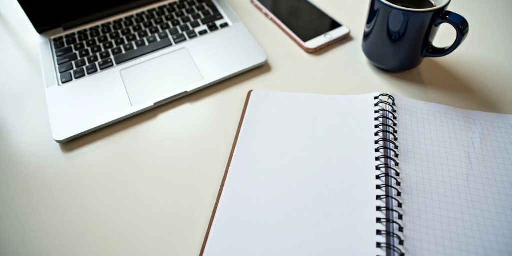 Clean workspace with laptop, notepad, and coffee cup.